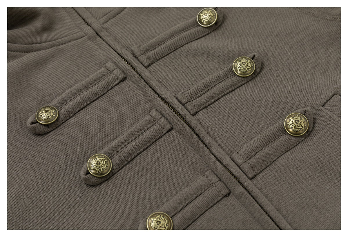 Close-up of the jacket’s front zipper and decorative brass crest buttons on fabric tabs.