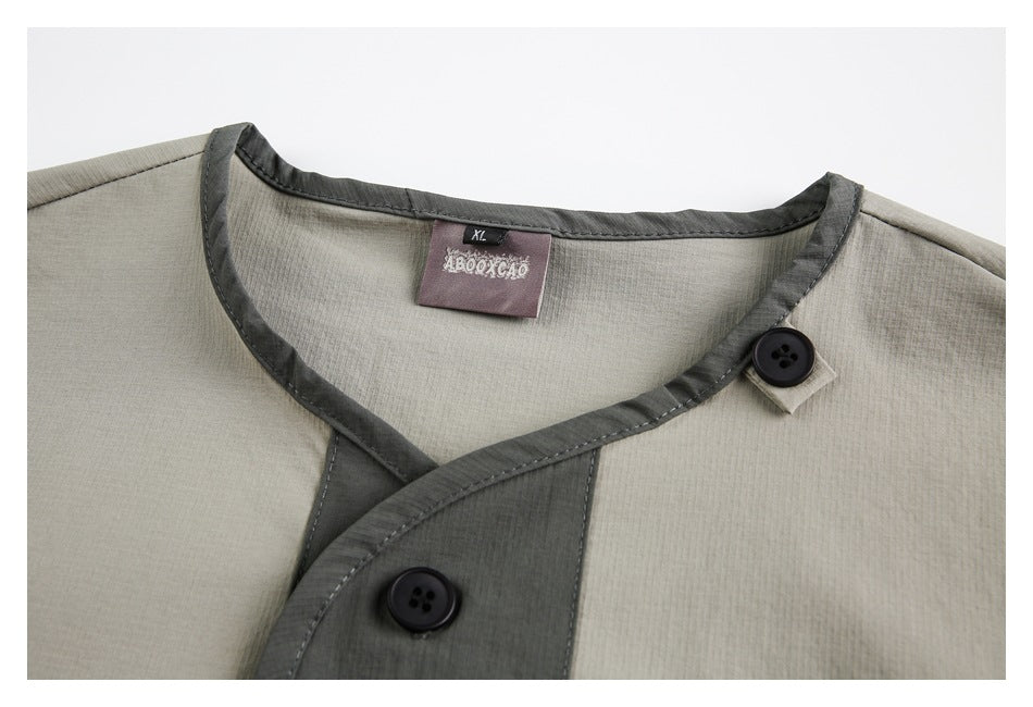 Close-up of a light gray garment's neckline, dark contrast edging, buttons, and sewn-in size label.