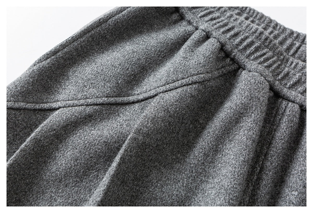 Close-up of charcoal gray trousers showing the elastic waistband and a curved pocket opening.