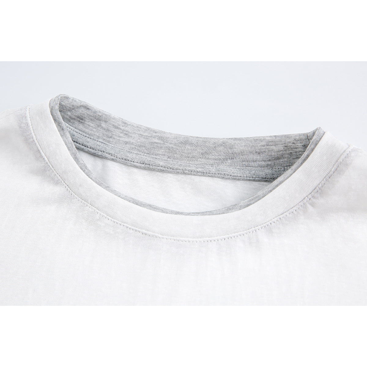 Close-up of a white top's round neckline with gray inner neck trim.