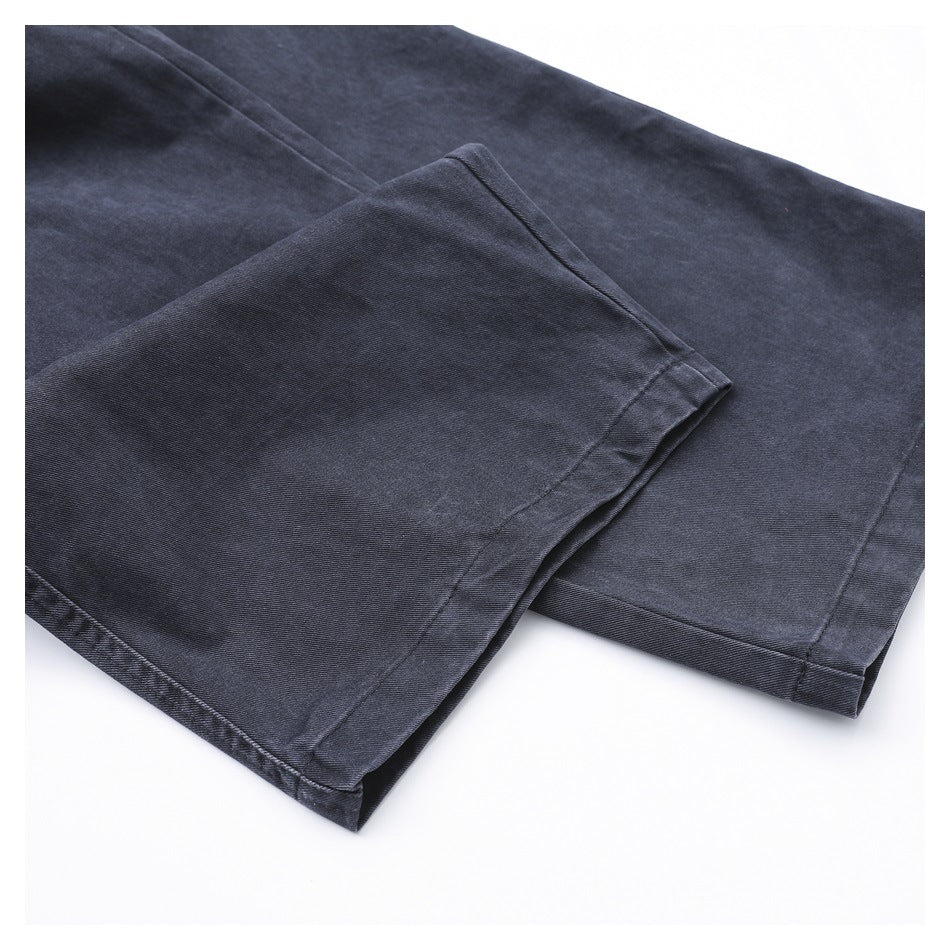 Close-up of dark charcoal pants showing two stitched leg hems and washed texture.