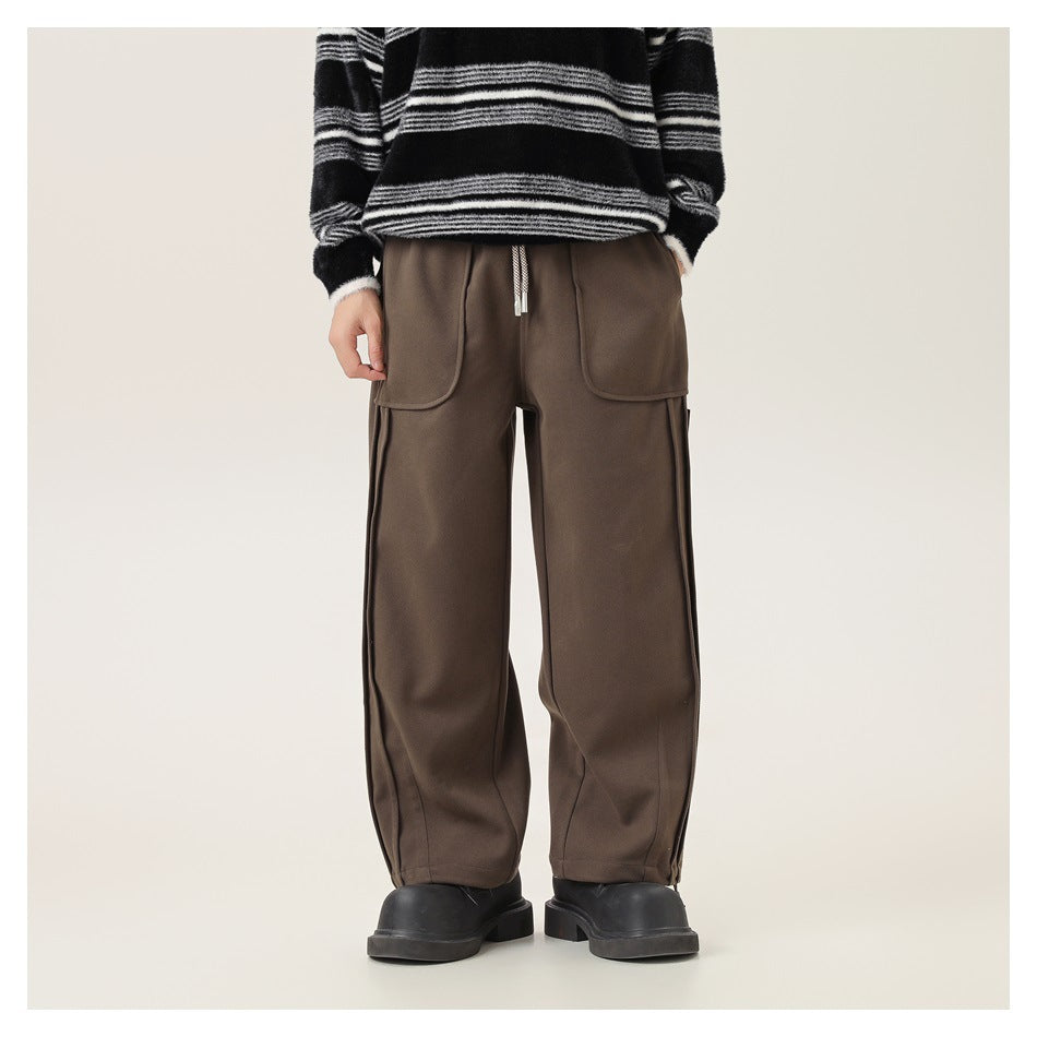 Front view of a model wearing loose brown drawstring pants with large front pockets and tapered cuffs.