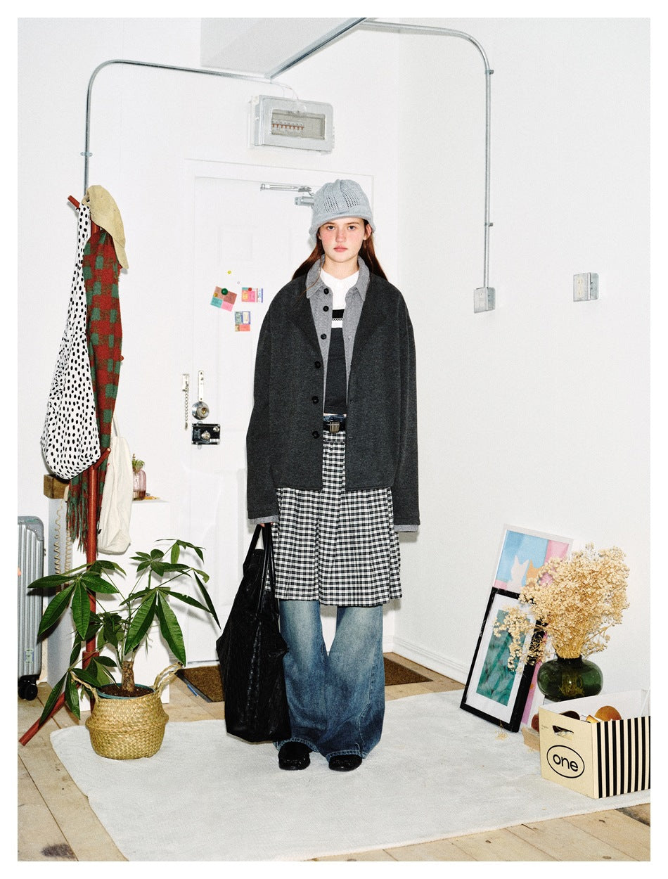Model wearing the dark gray layered-collar jacket over a plaid skirt and wide-leg jeans, front view