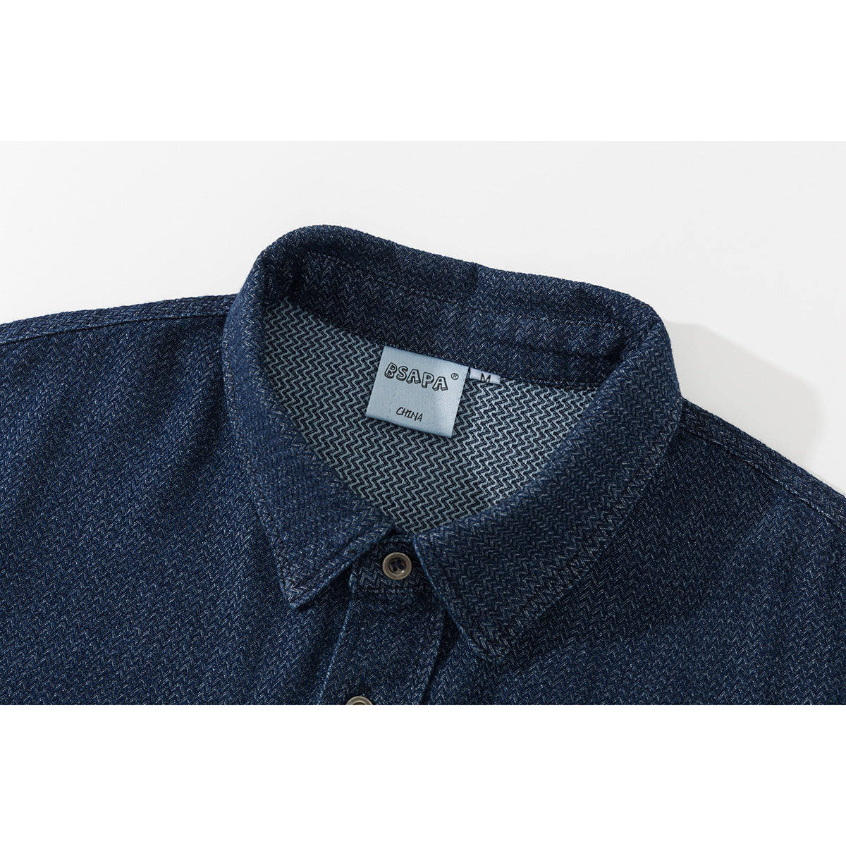 Close-up of a dark blue patterned shirt collar, buttons, and neck label.