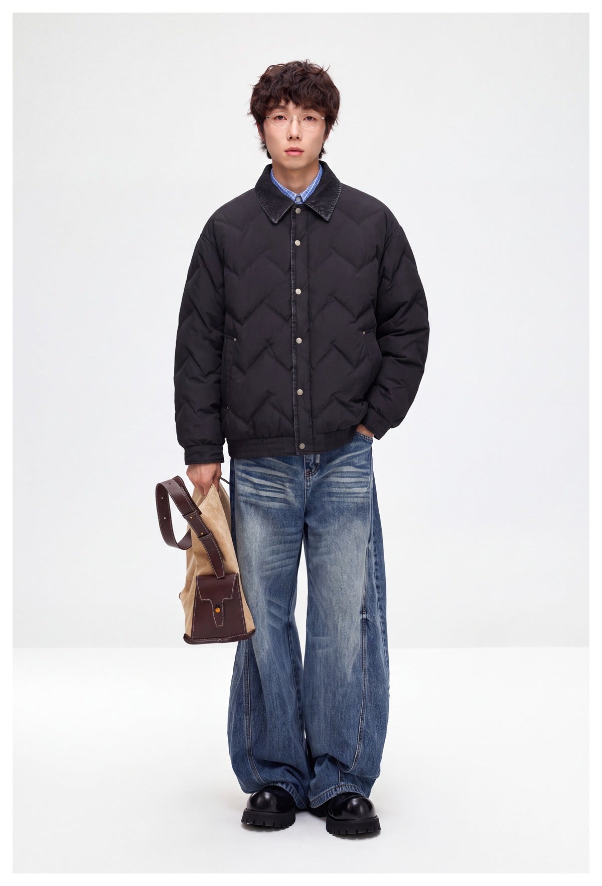 A model wears a black zigzag-quilted jacket with a dark pointed collar and snap front.