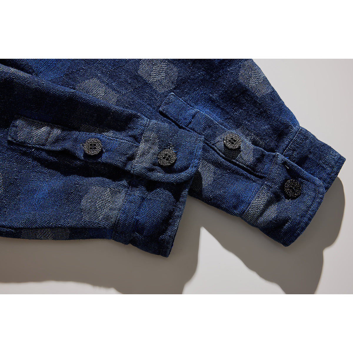 Close-up of the dark blue patterned shirt sleeve cuffs and dark buttons.