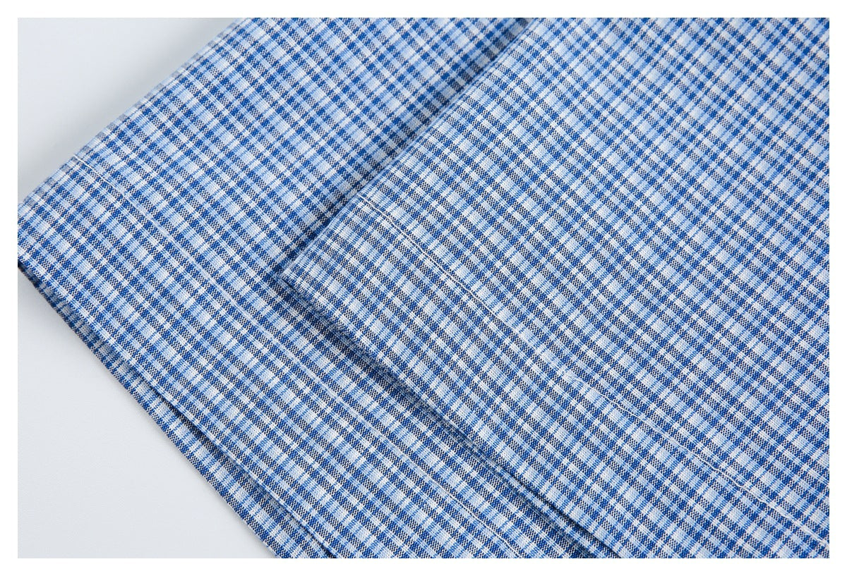 Close-up of blue-and-white checked garment fabric showing a stitched seam and folded edge.