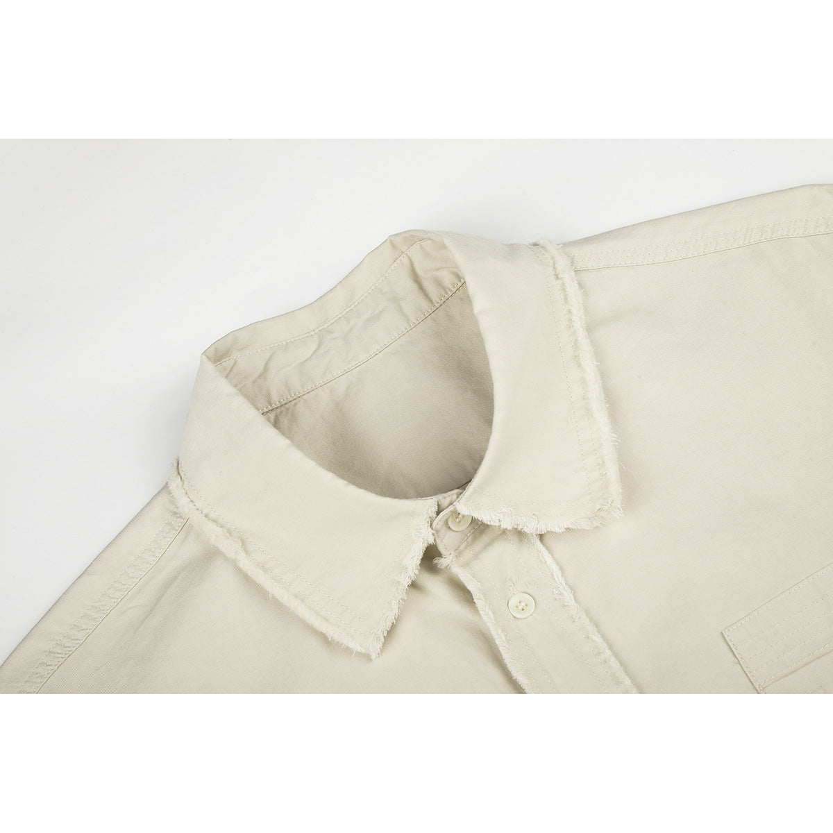 Close-up of an off-white shirt collar and button placket with frayed edges.