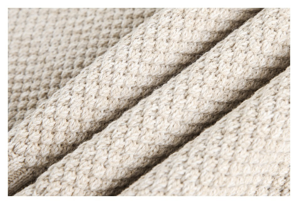 Macro view of the cream sweater's chunky knit texture, with fabric folded into ridges.