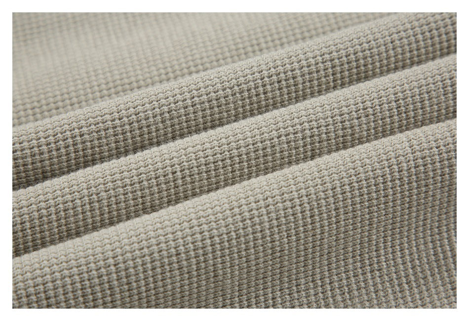 Macro view of the pullover's light beige, raised grid-like fabric texture.