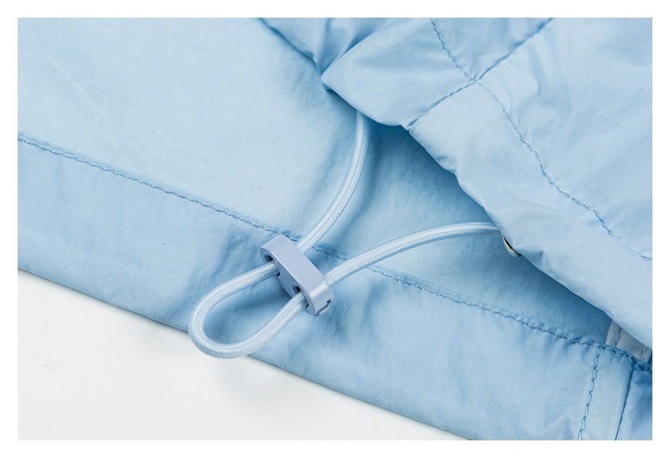 Close-up of a light blue garment's white elastic drawcord and plastic toggle.