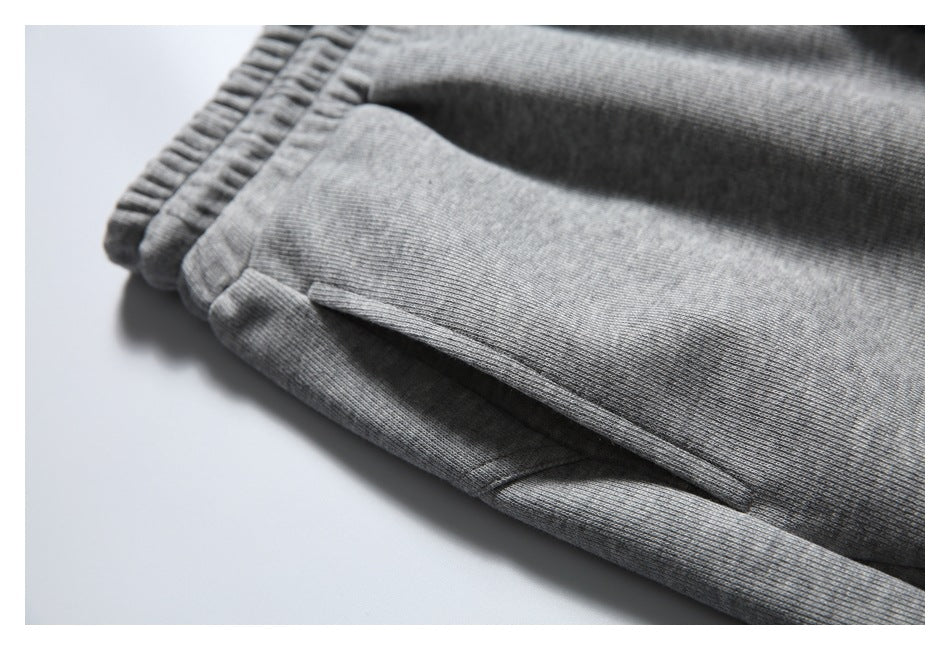 Close-up of a slanted pocket opening and stitching on gray jogger pants.