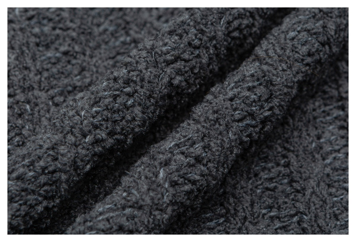 Macro view of the dark charcoal garment's thick, textured knit stitches.