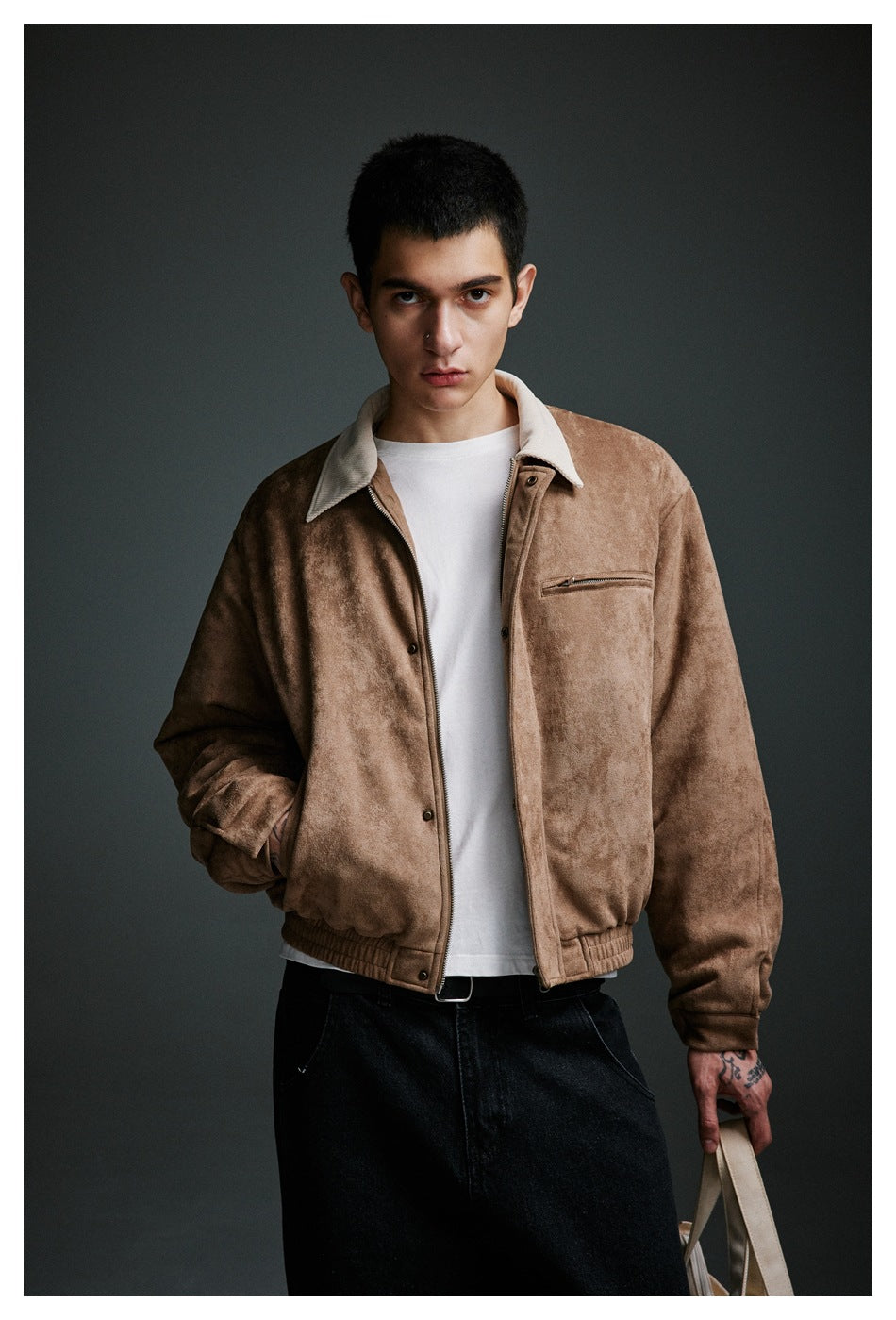 Front view of a man modeling a tan jacket with a cream collar, zip chest pocket and elastic hem over a white shirt.