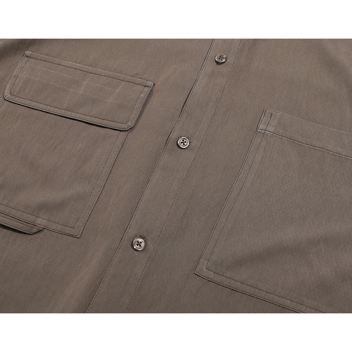 Close-up of a brown shirt's two front patch pockets, stitching, and button placket.
