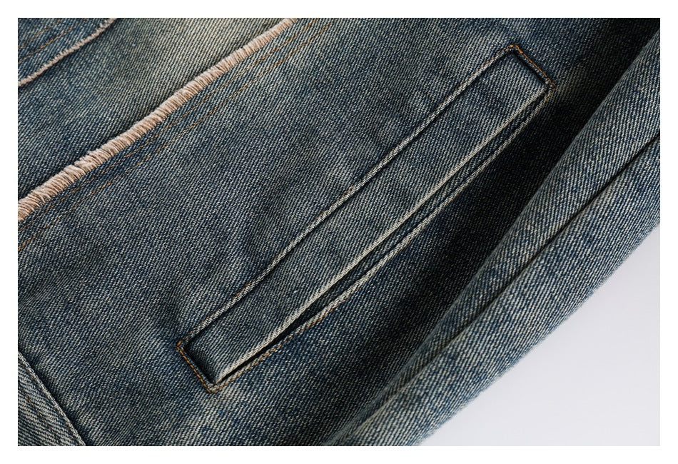 Close-up of a narrow welt pocket and orange stitching on faded blue denim.