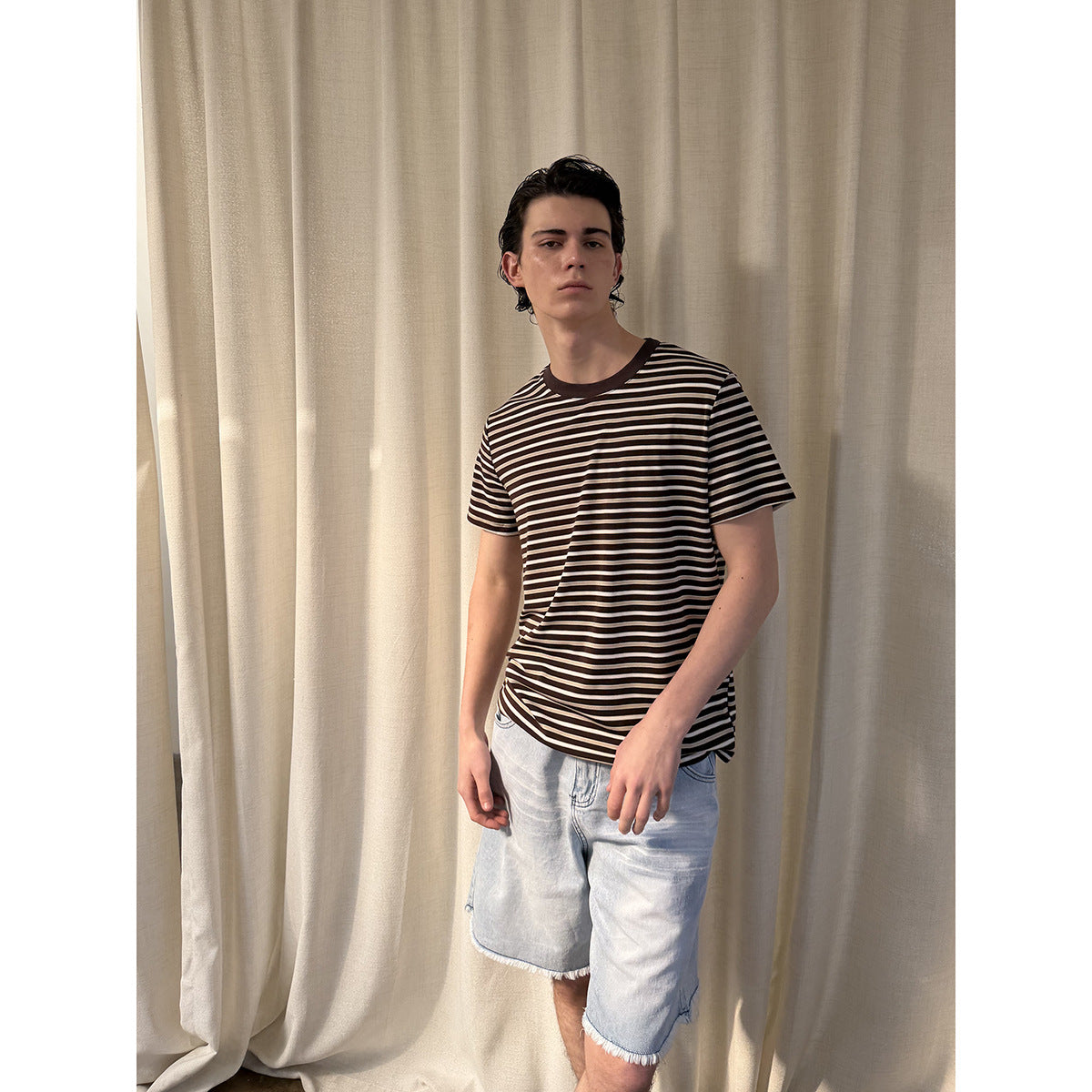 Model wearing a dark brown and cream horizontally striped T-shirt with a brown crew neck.