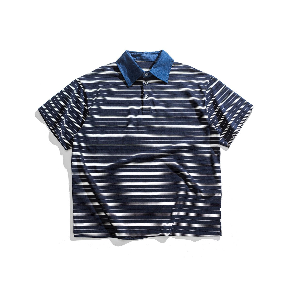 Navy polo shirt with white multi-line stripes, blue denim-look collar and three-button placket, laid flat