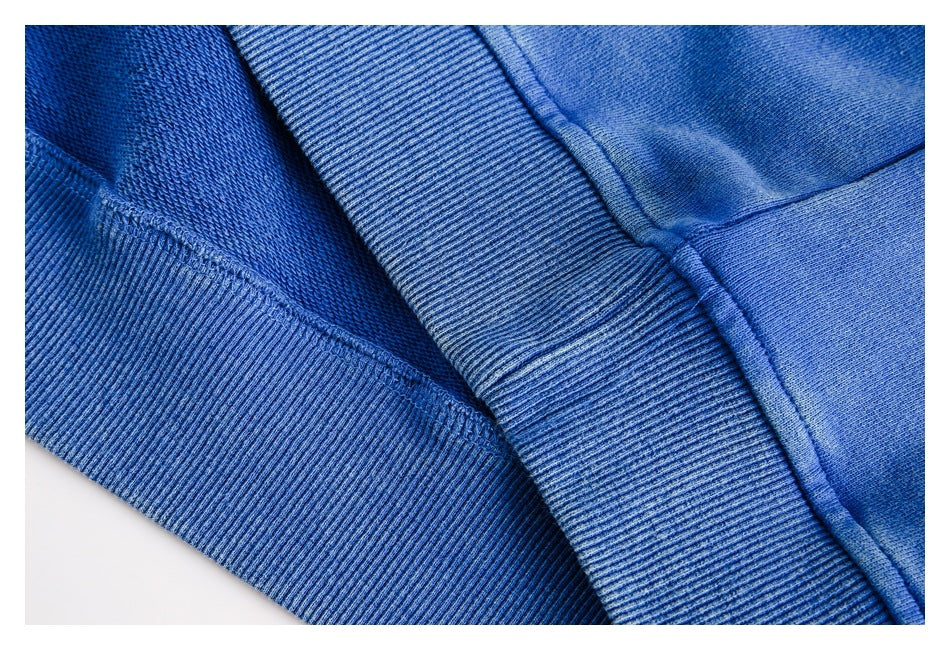 Close-up of a blue sweatshirt's ribbed hem, interior knit, and stitched seams.