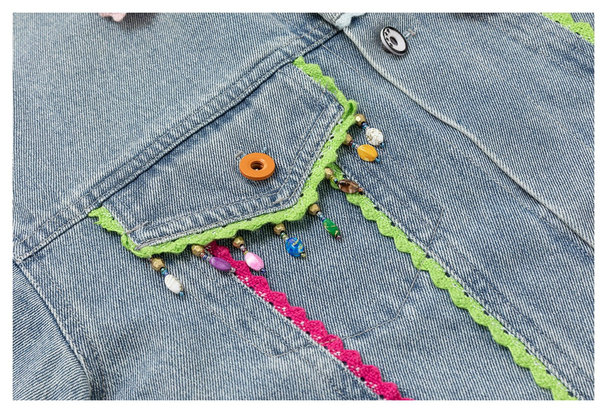 Close-up of denim jacket pockets with lime and pink scalloped trim and colorful dangling beads.