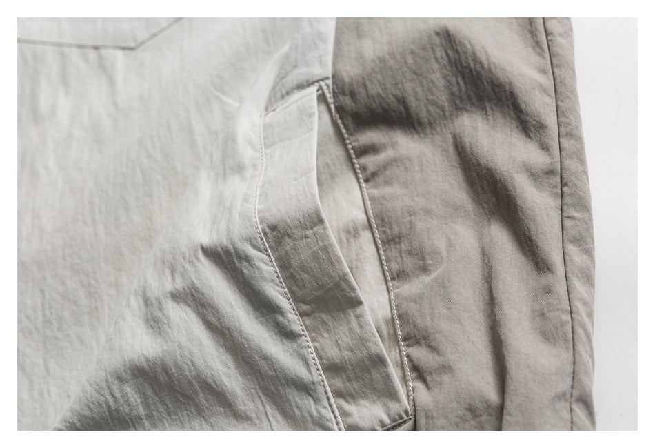 Close-up of a side pocket opening and stitching on a light neutral garment.