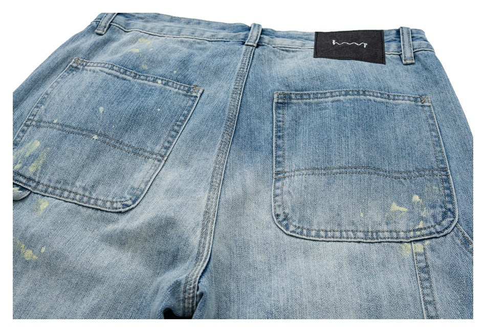 Close view of the back of light blue jeans with two patch pockets, pale distressed marks, and a black waistband patch.