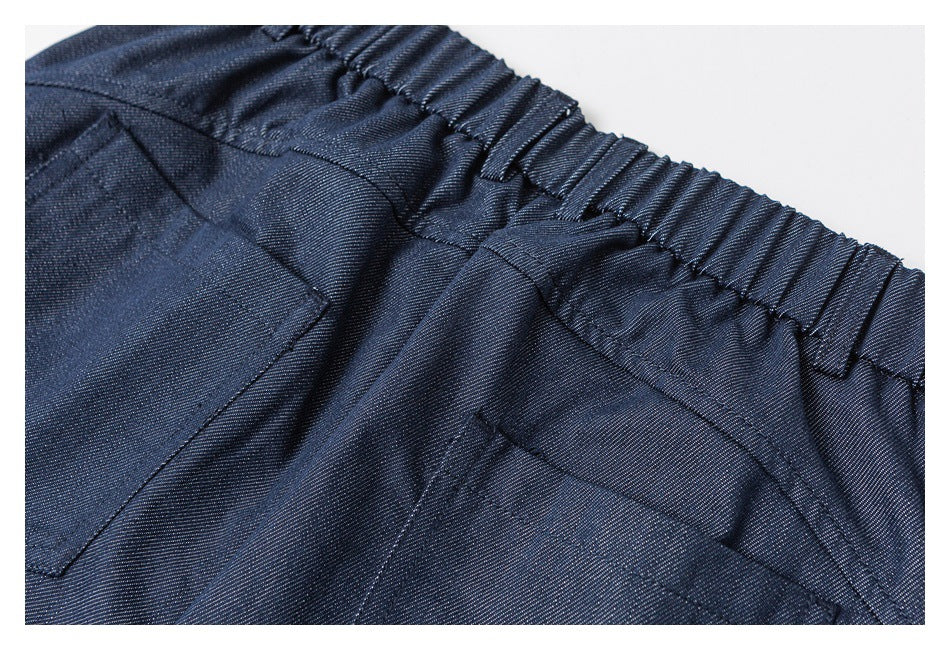 Close-up of the back of navy trousers, showing the gathered waistband and stitched rear pockets.