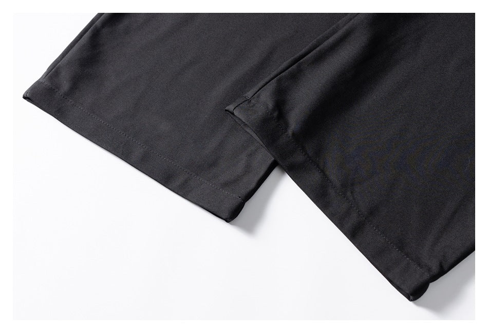 Close-up of the hems and stitching on two sections of black garment fabric.