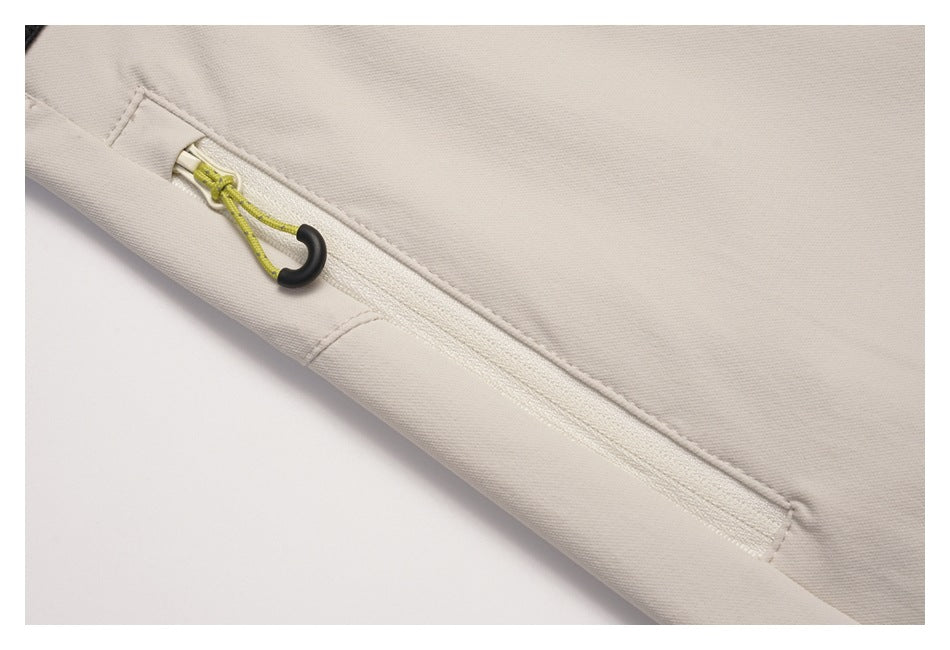 Close-up of a light beige garment pocket with a pale zipper and lime cord pull with a black ring.
