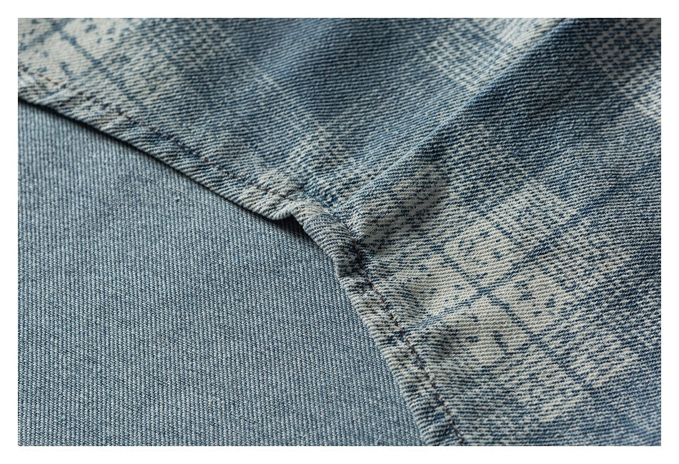 Close-up of a stitched seam joining blue-and-white patterned denim panels.