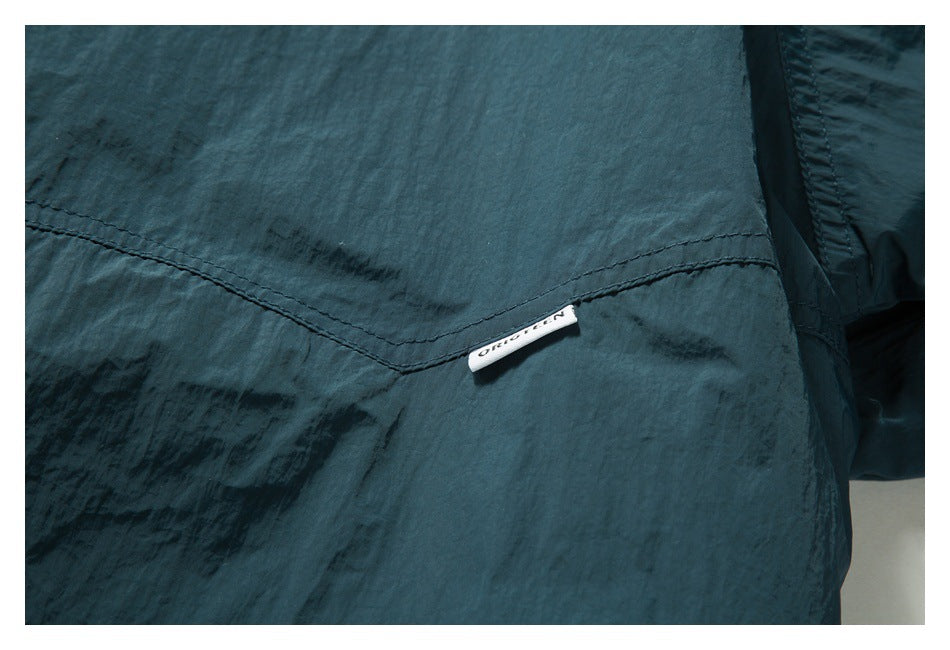 Close-up of a curved seam and small sewn label on dark teal fabric.