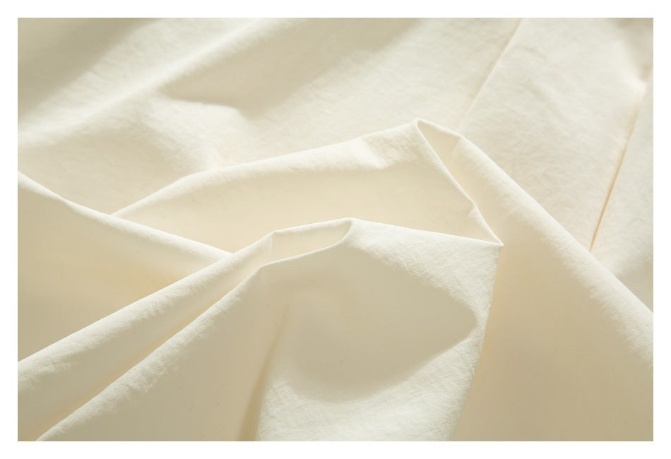 Close-up of softly folded ivory garment fabric and a stitched edge.