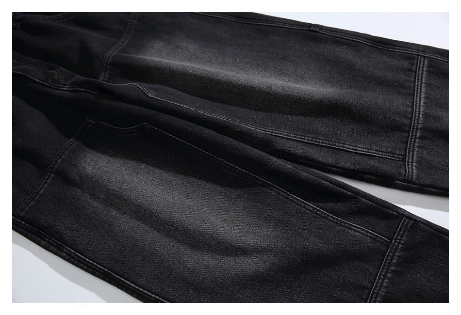 Close-up of black jeans legs laid diagonally, showing the fabric finish and stitched seams.