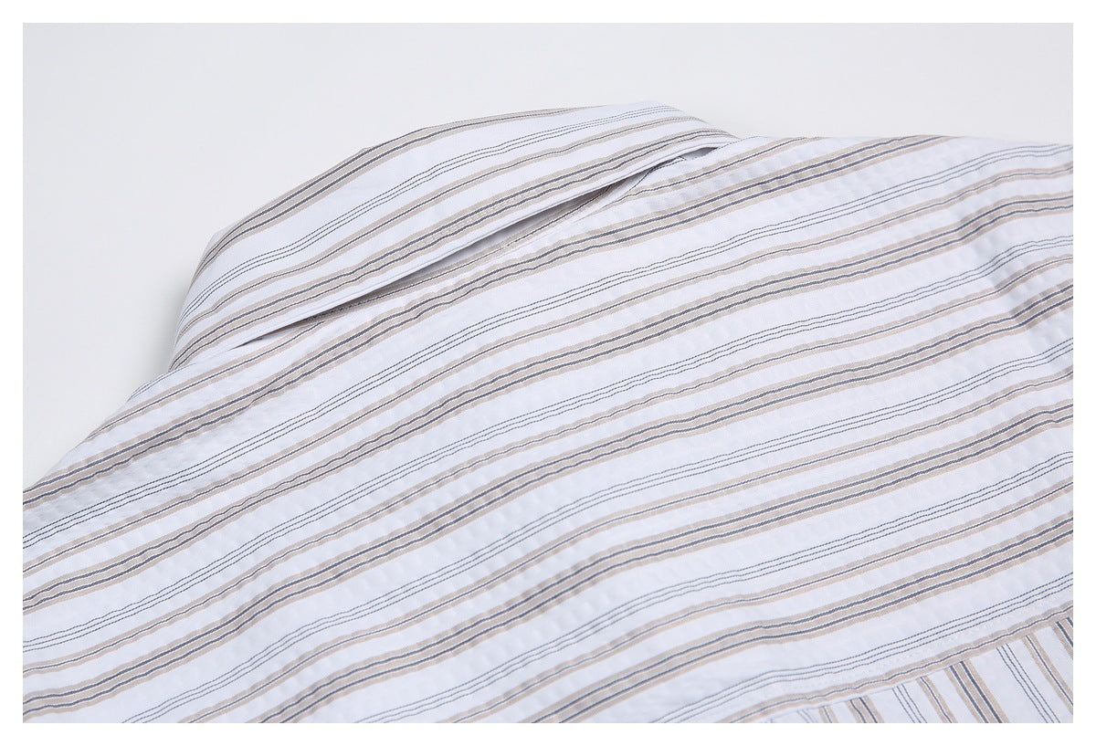 Close-up of a folded white shirt collar and fine gray and beige stripes.
