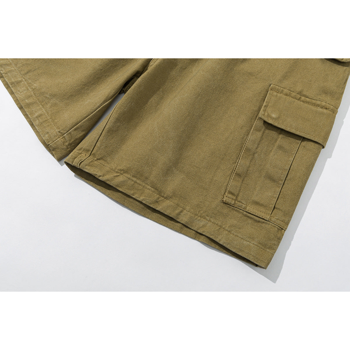 Close-up of olive cargo shorts showing a flap cargo pocket and stitched hem.