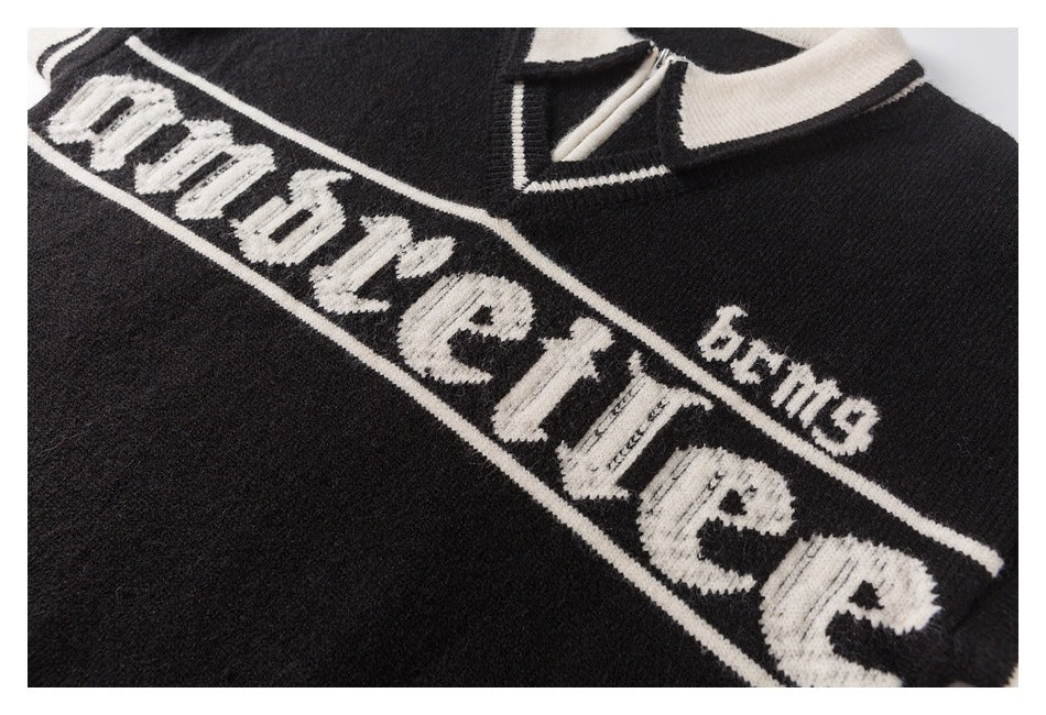 Close-up of a black sweater with ivory chest lettering and a small matching text detail.