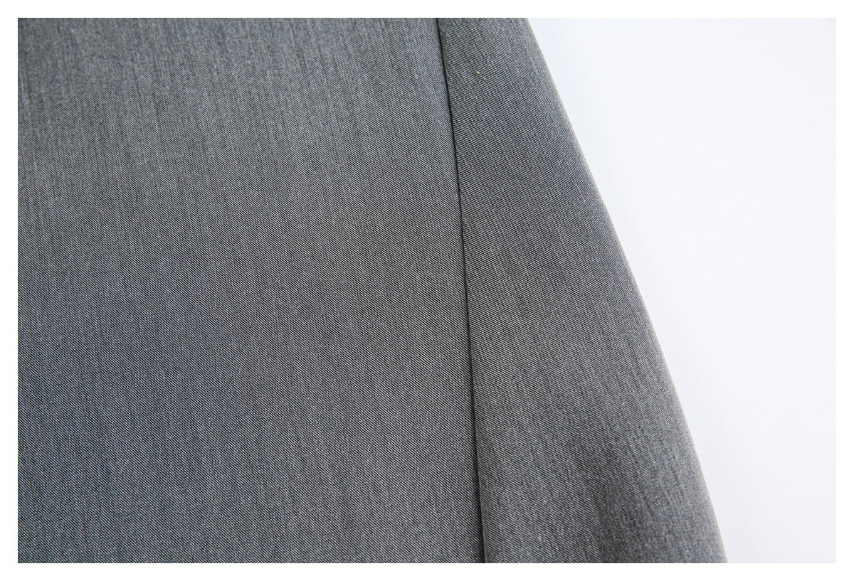 Close-up of charcoal-gray trouser fabric with a seam and curved garment edge.
