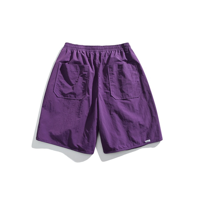 Back view of purple shorts with an elastic waistband and two large rear patch pockets, on a white background.