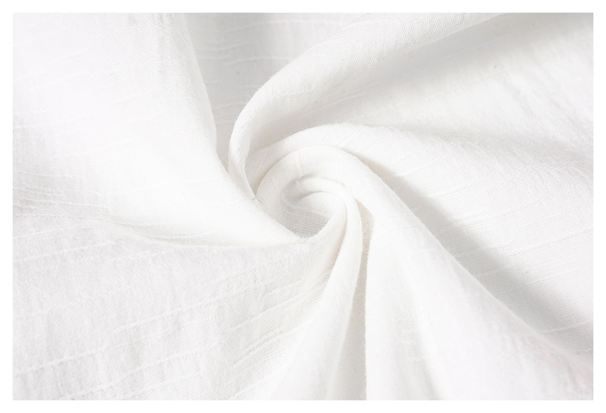 Close-up of white woven fabric gathered into a swirl, showing its subtle texture and weave.