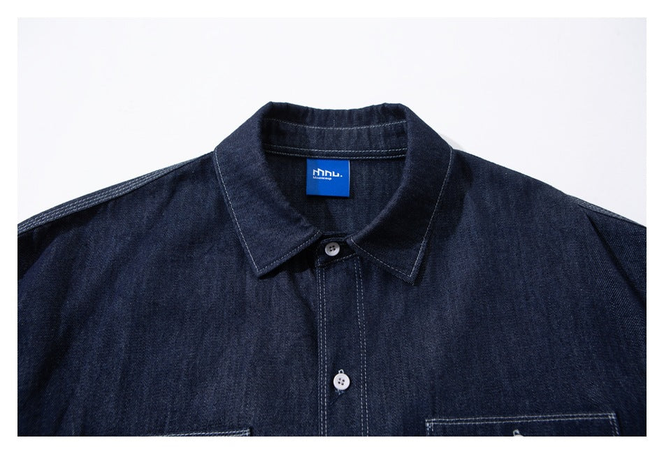 Close-up of a dark indigo shirt collar and upper chest, with white buttons, contrast stitching, and a blue neck label.