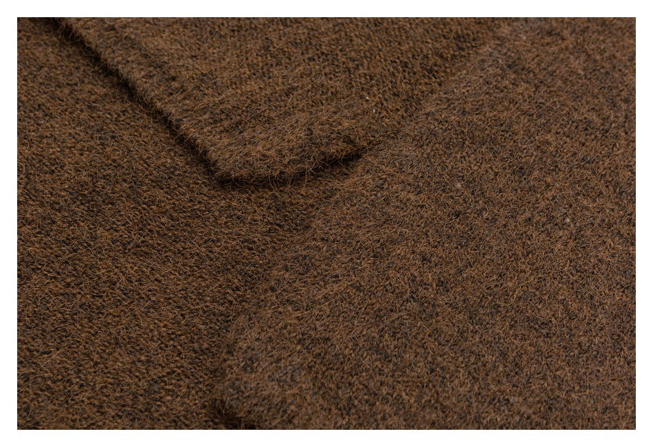 Close-up of brown fuzzy knit fabric showing a raised seam or folded edge.