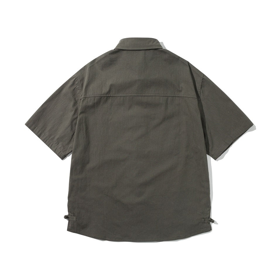 Back view of an olive-gray short-sleeve button-up shirt with a horizontal yoke seam and ties at the lower sides.