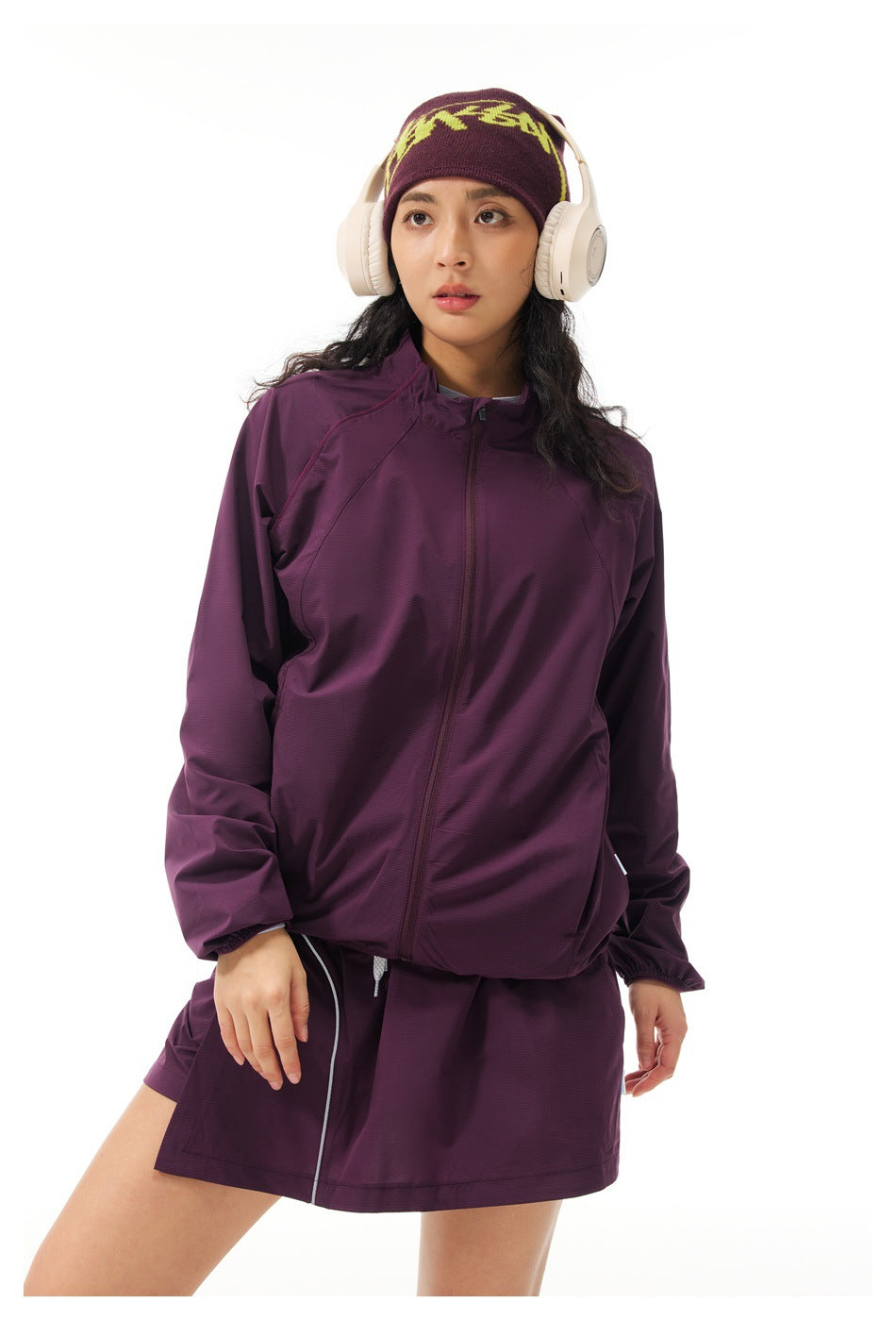 Model wearing a zipped plum jacket and matching skirt, shown from the thighs up.
