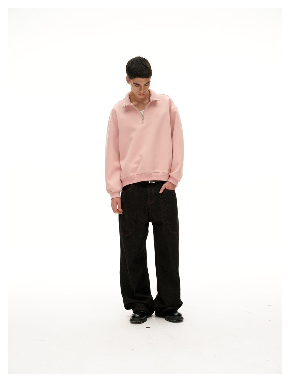 Front view of a model wearing a pale pink quarter-zip pullover with a folded collar and loose black jeans.