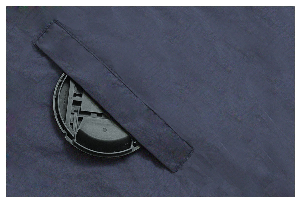 Close-up of dark navy fabric with a stitched flap over a round plastic piece.