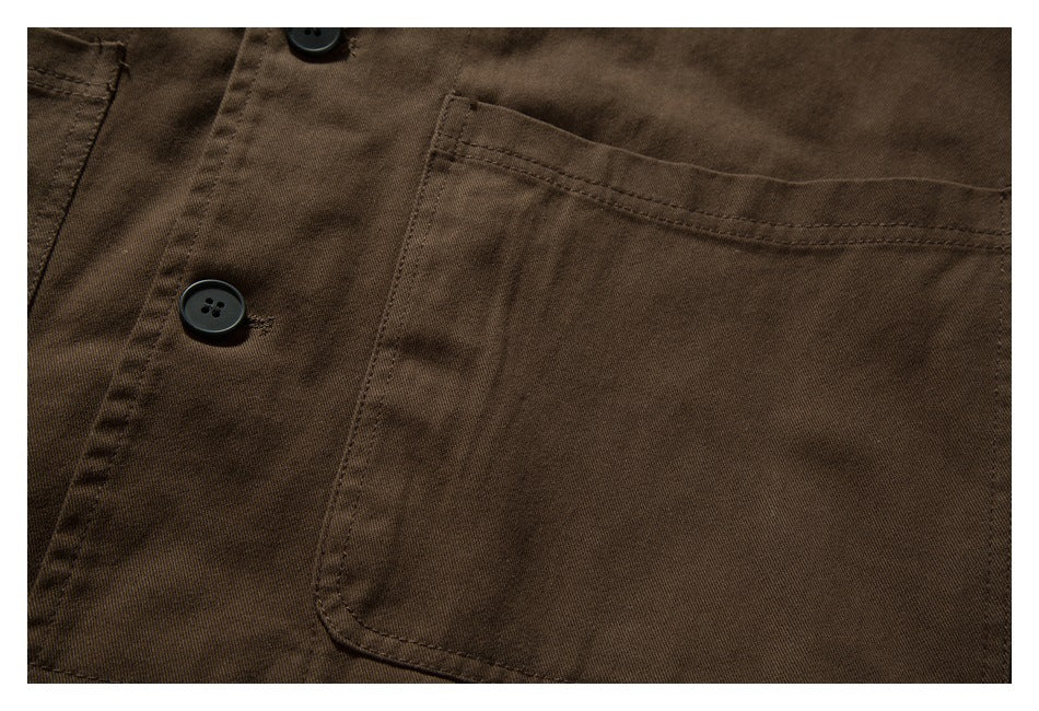 Close-up of a brown garment with a large stitched pocket and black buttons.