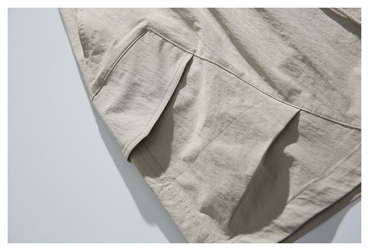Close-up of a flap cargo pocket and stitched paneling on light beige shorts.