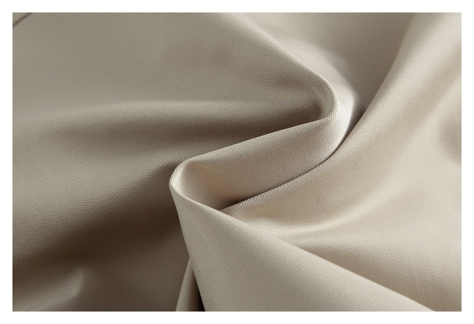 Close-up of light beige fabric draped in soft folds, showing a fine diagonal weave.