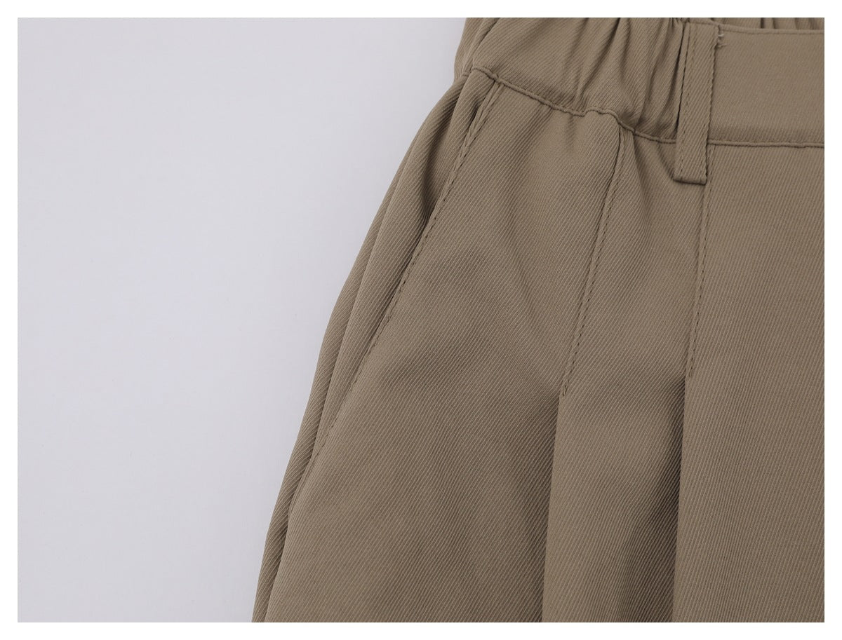 Close-up of taupe trousers showing a belt loop, waistband seam, and side pocket edge.