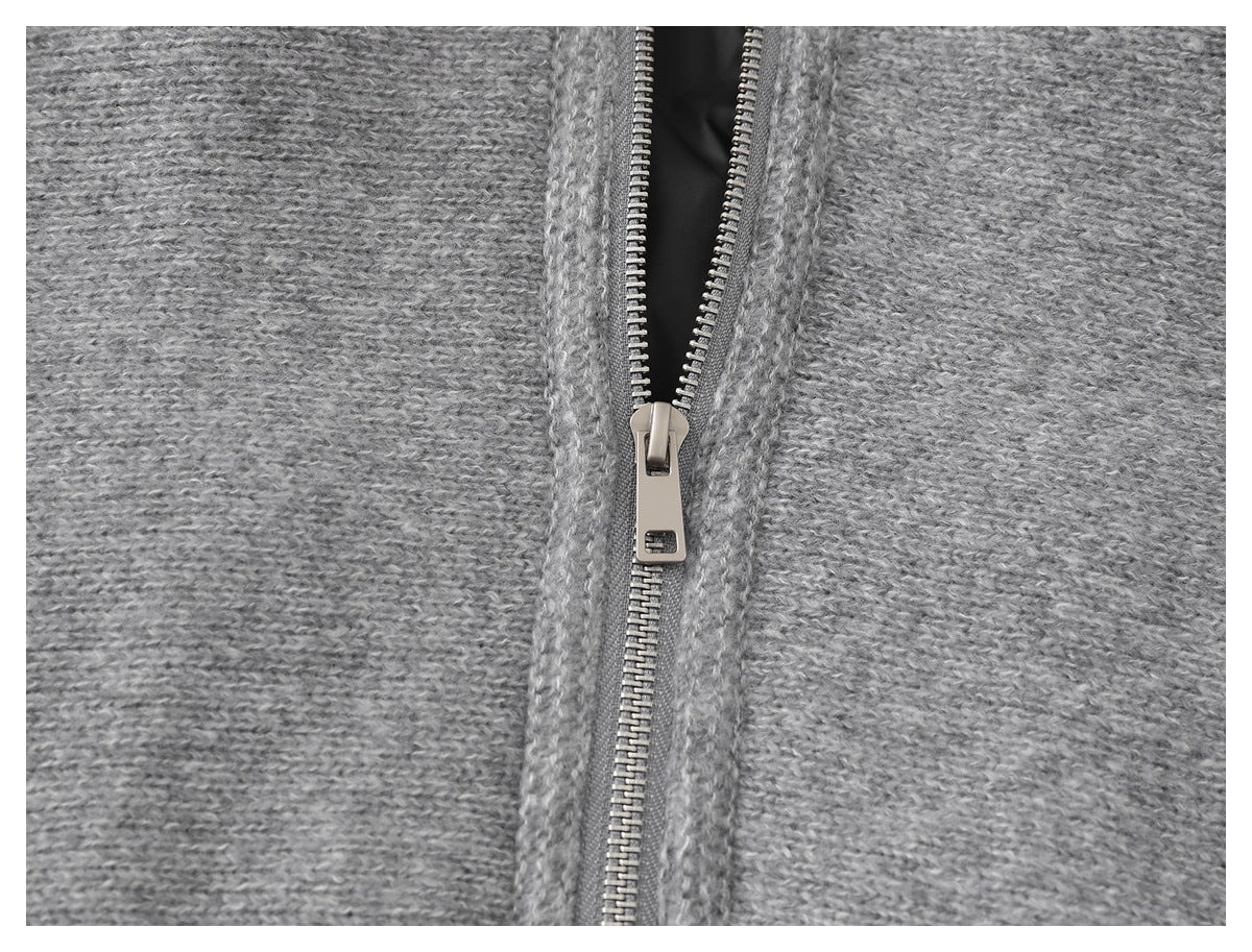 Close-up of a silver zipper on a gray knit garment, showing the textured knit and zipper pull.